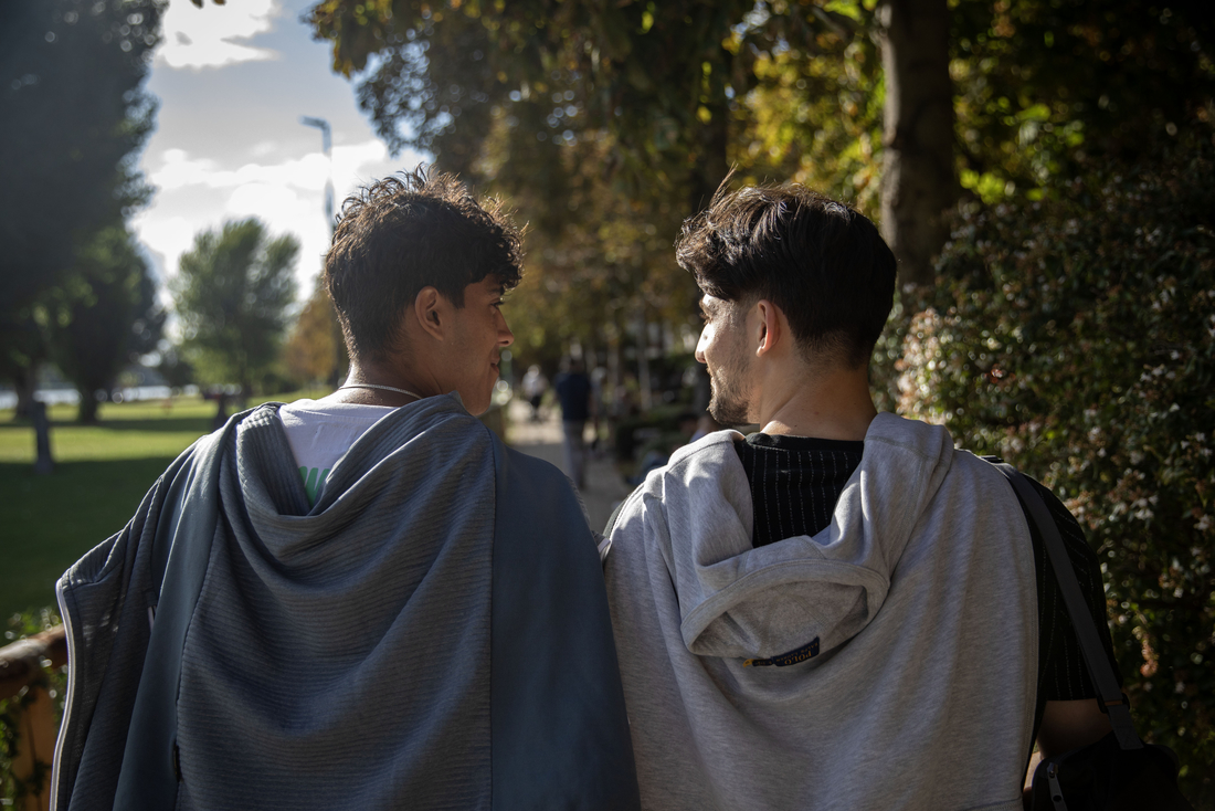 Zwei junge Männer, die sich anschauen und durch einen Park laufen.